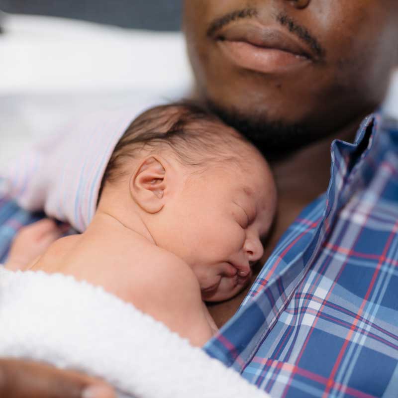 Père afro-américain tenant un nouveau-né sur sa poitrine, contact peau à peau